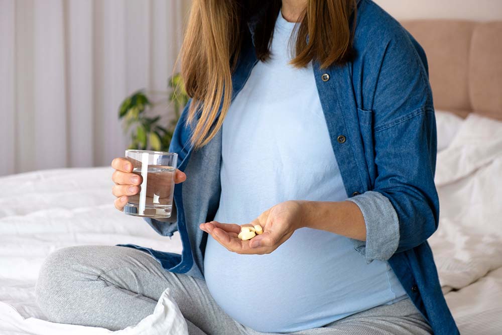 Беременная женщина, стакан воды и таблетки