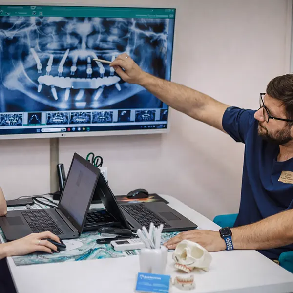 Имплантолог показывает снимок челюсти после имплантации