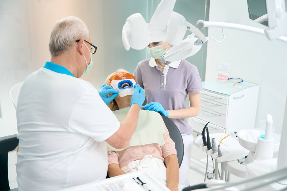 Стоматолог проводит повторное эндодонтическое лечение зубов под коронками
