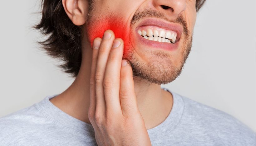Мужчина с болью в челюсти после удаления зуба