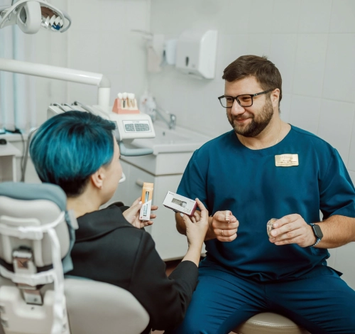 Хирург-имплантолог показывает пациентке импланты Noris Medical и Neodent.